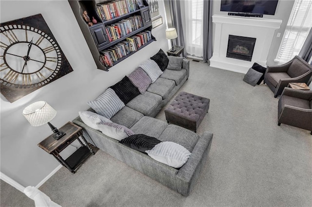 carpeted living room featuring baseboards and a glass covered fireplace