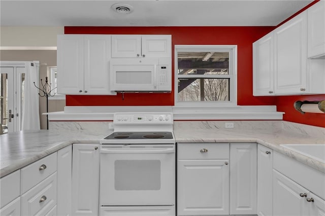 kitchen featuring white appliances, visible vents, and white cabinetry