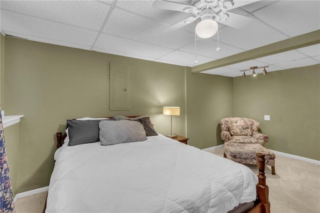 carpeted bedroom featuring a paneled ceiling, electric panel, baseboards, and a ceiling fan