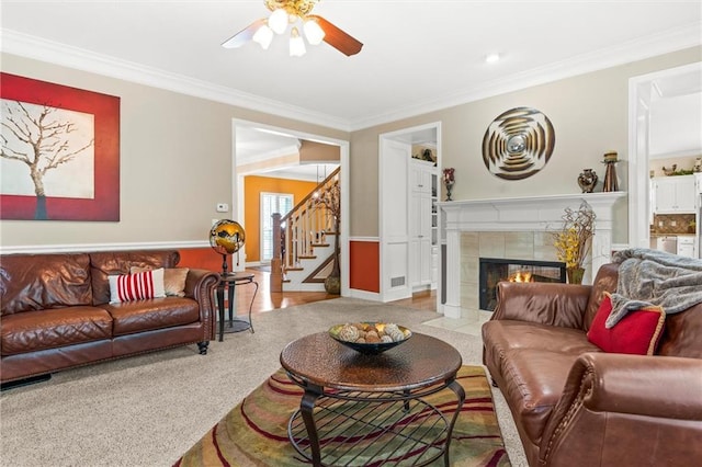 carpeted living room with ceiling fan, ornamental molding, and a fireplace