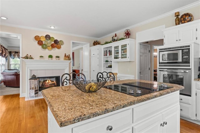 kitchen with white cabinetry, light stone countertops, stainless steel appliances, and a kitchen island