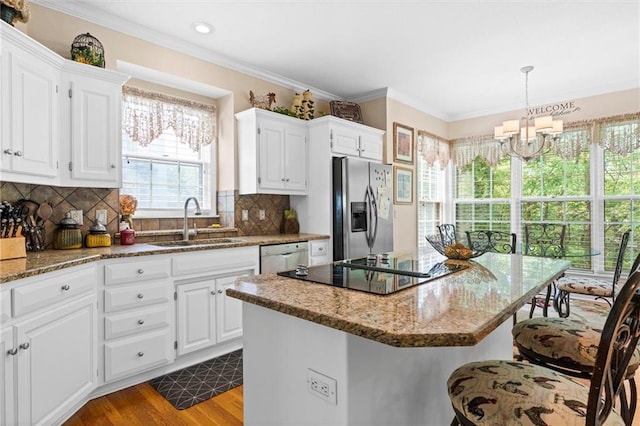 kitchen featuring sink, stainless steel appliances, a center island, and white cabinets