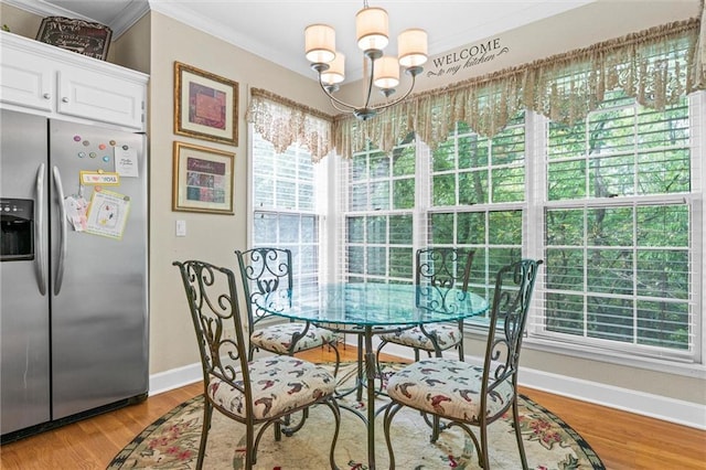 dining space with crown molding, light hardwood / wood-style floors, and a notable chandelier