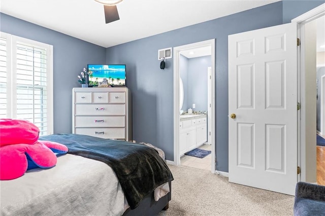 bedroom featuring ensuite bathroom, light colored carpet, and ceiling fan