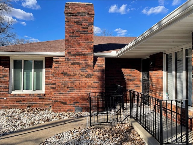 view of home's exterior featuring brick siding, a chimney, and a shingled roof