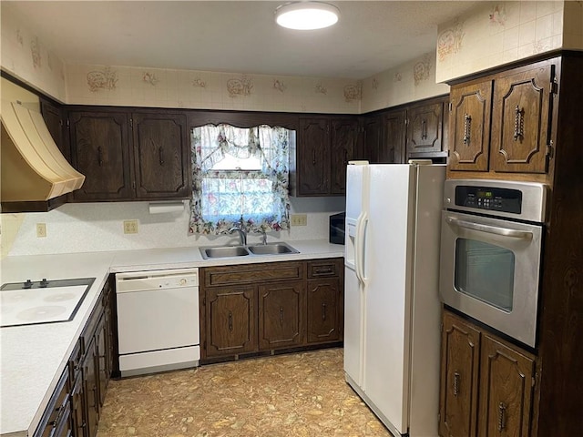 kitchen with light countertops, white appliances, a sink, and dark brown cabinetry