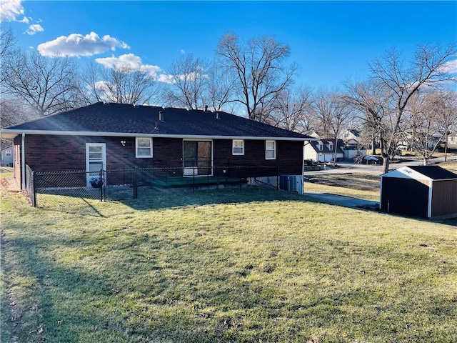 rear view of house with brick siding, a lawn, and fence