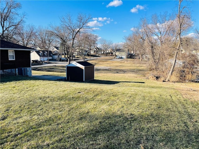 view of yard with a shed, a residential view, cooling unit, and an outbuilding