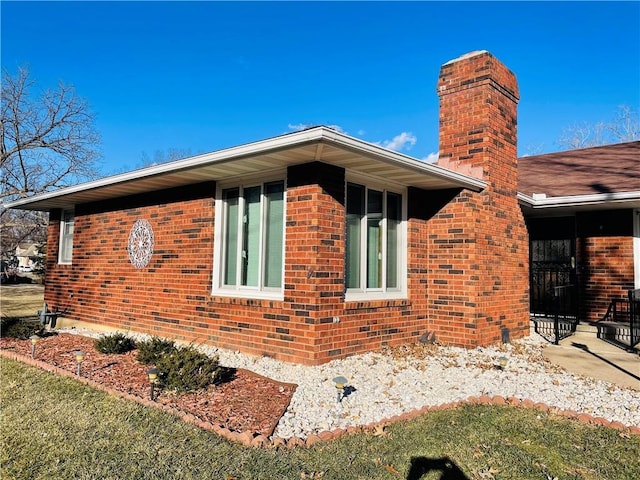 view of property exterior featuring brick siding and a chimney