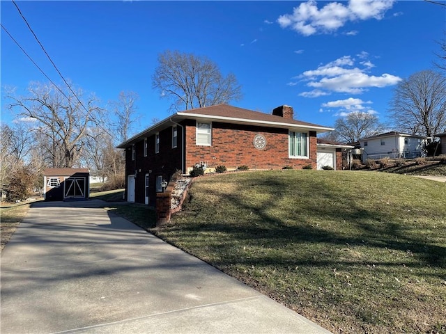 view of side of home with brick siding, an outdoor structure, driveway, a lawn, and a chimney