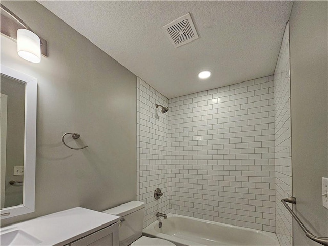 full bathroom featuring vanity, a textured ceiling, toilet, and tiled shower / bath