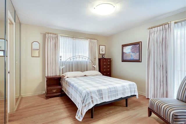 bedroom featuring light wood finished floors and baseboards