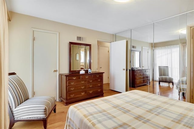 bedroom with light wood finished floors and visible vents