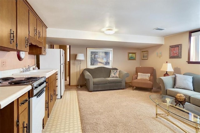 interior space with visible vents, brown cabinetry, electric range oven, open floor plan, and light countertops