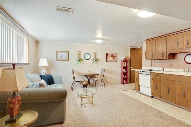 kitchen featuring visible vents, light countertops, white gas stove, light floors, and a sink