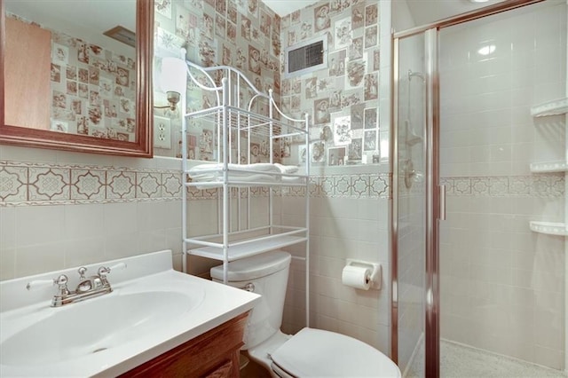 full bathroom with wallpapered walls, toilet, vanity, a shower stall, and tile walls