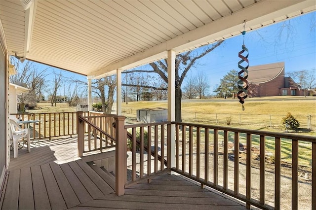 wooden deck featuring a shed, a fenced backyard, a lawn, and an outbuilding