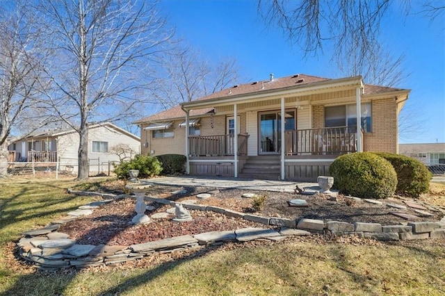 bungalow-style home featuring covered porch, brick siding, and fence