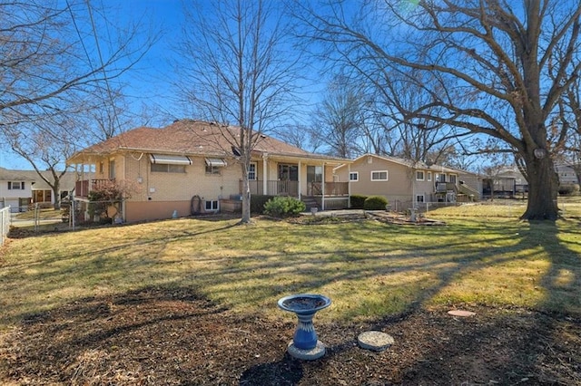 rear view of house with brick siding, fence, and a lawn