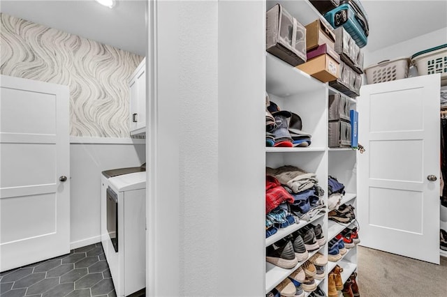 washroom featuring dark tile patterned flooring, washing machine and dryer, and cabinet space