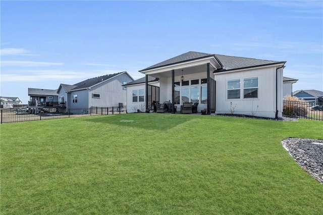 back of house with a fenced backyard, a residential view, and a yard