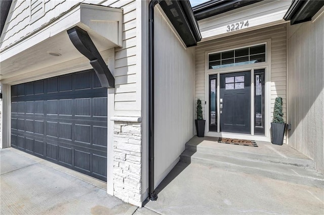 view of exterior entry featuring a garage and concrete driveway