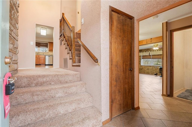 stairs with a high ceiling, tile patterned floors, and ceiling fan