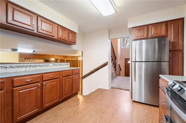 kitchen with appliances with stainless steel finishes, ceiling fan, and light hardwood / wood-style flooring