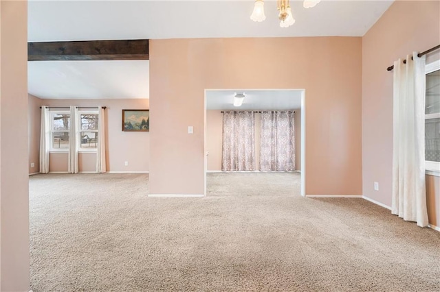 carpeted spare room featuring an inviting chandelier and beam ceiling