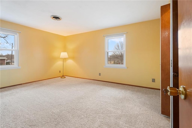 unfurnished room with light colored carpet and plenty of natural light