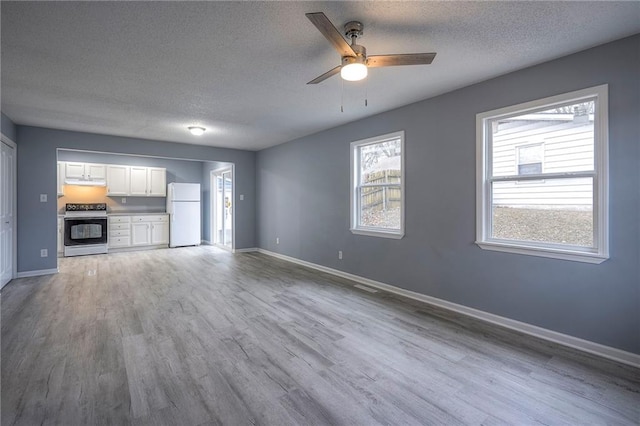 unfurnished living room with ceiling fan, light hardwood / wood-style flooring, and a textured ceiling