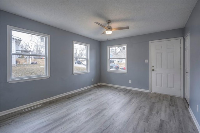 spare room featuring ceiling fan, light hardwood / wood-style flooring, and a textured ceiling