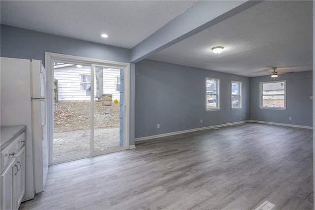 interior space with ceiling fan, a textured ceiling, and light wood-type flooring