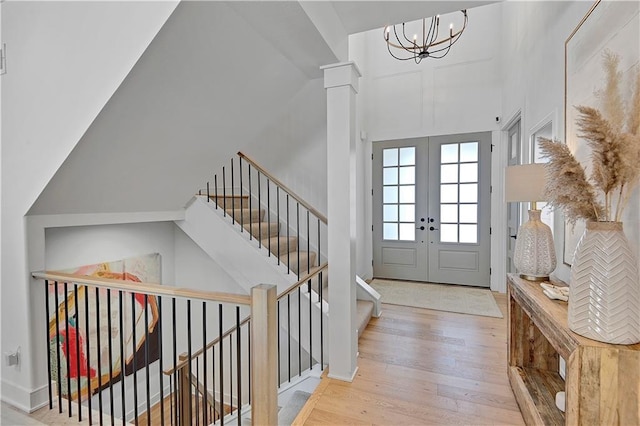 foyer entrance with french doors, a notable chandelier, a high ceiling, and wood finished floors