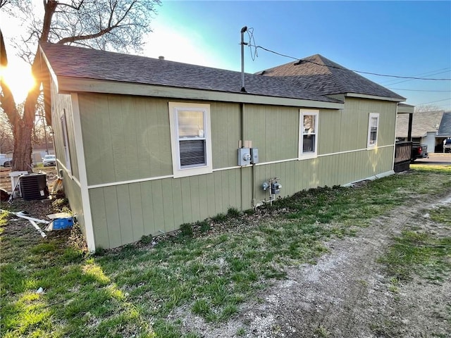 view of side of home featuring central AC and a lawn