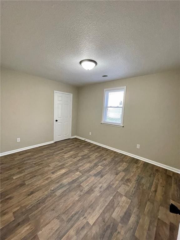 empty room with dark wood-type flooring and a textured ceiling