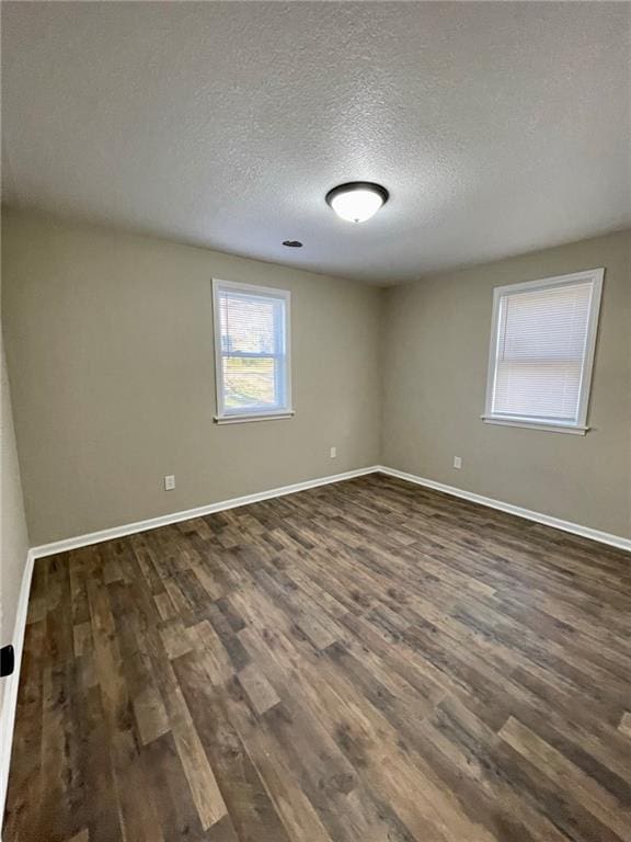 empty room featuring dark hardwood / wood-style floors and a textured ceiling