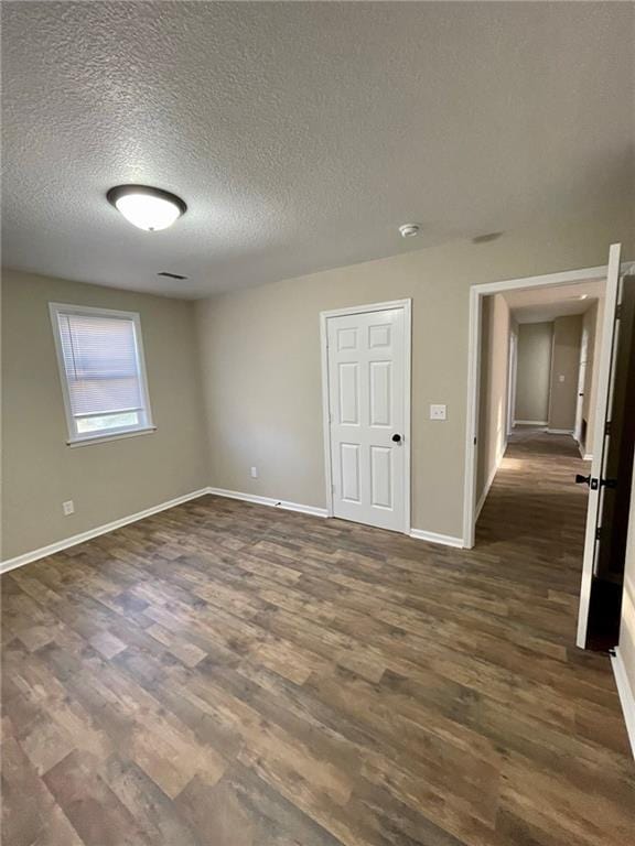 unfurnished room with a textured ceiling and dark hardwood / wood-style flooring