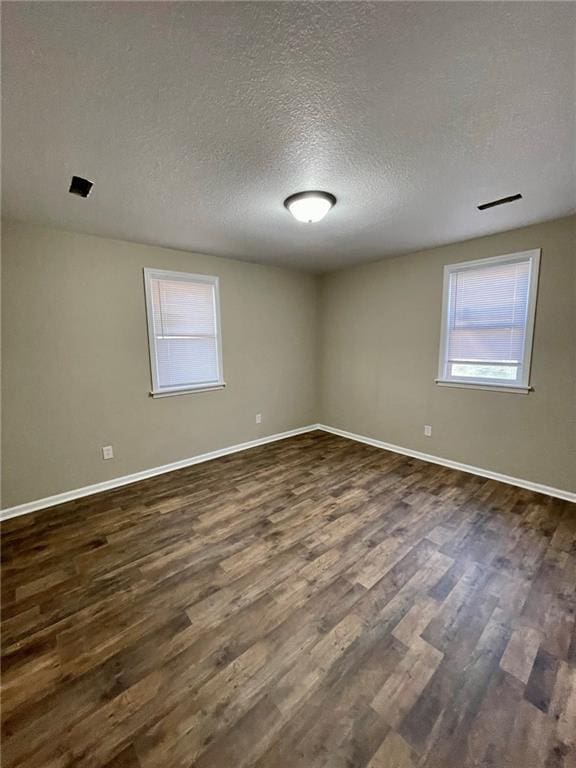 spare room with dark hardwood / wood-style flooring and a textured ceiling