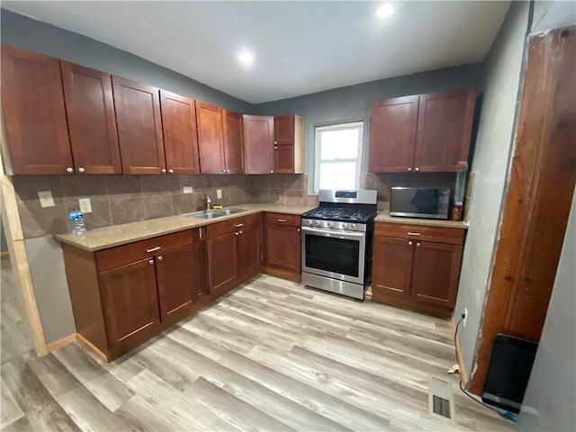 kitchen featuring appliances with stainless steel finishes, light hardwood / wood-style floors, sink, and decorative backsplash