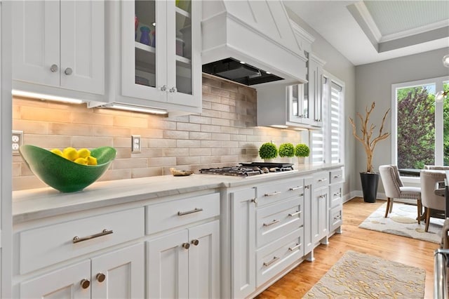 kitchen featuring stainless steel gas cooktop, white cabinets, light wood-type flooring, and premium range hood