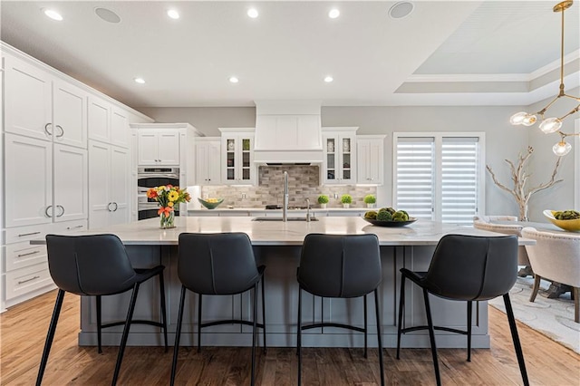 kitchen with white cabinetry, wood finished floors, a spacious island, and stainless steel appliances