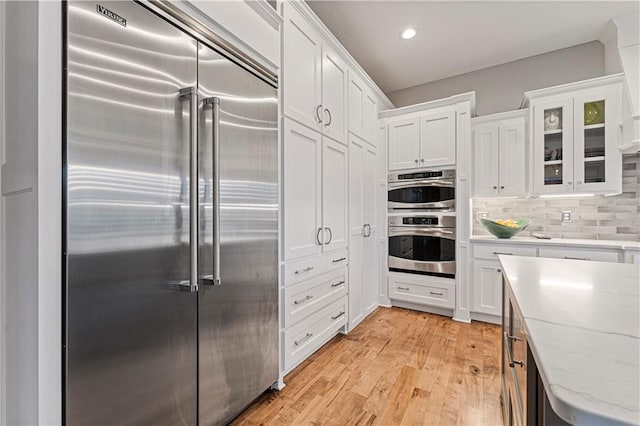 kitchen featuring light wood finished floors, appliances with stainless steel finishes, and white cabinetry