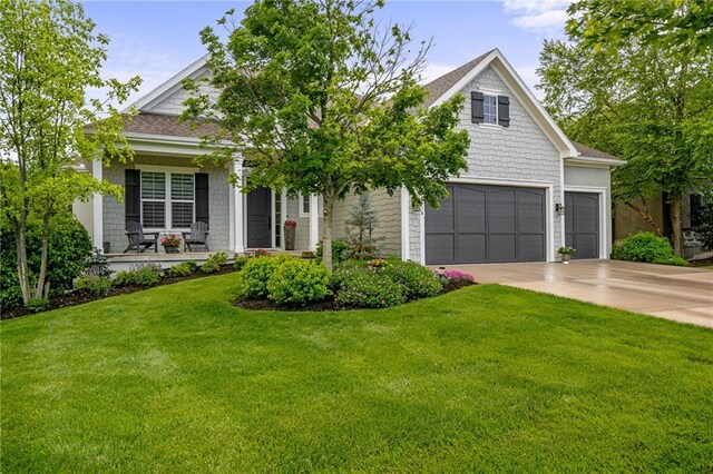 view of front of home with a porch, an attached garage, a front lawn, and driveway