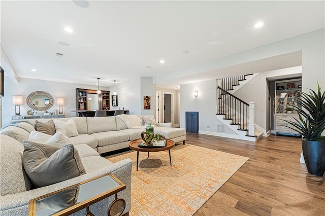 living room with wood finished floors, visible vents, baseboards, recessed lighting, and stairs