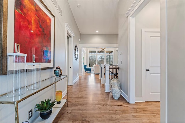 corridor with recessed lighting, baseboards, wood finished floors, and an upstairs landing