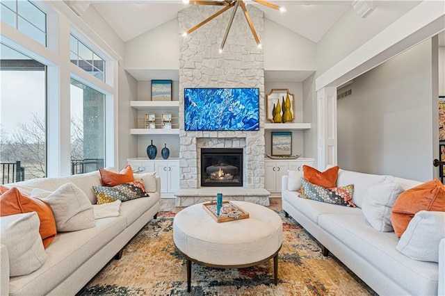 living room featuring built in shelves, high vaulted ceiling, and a fireplace