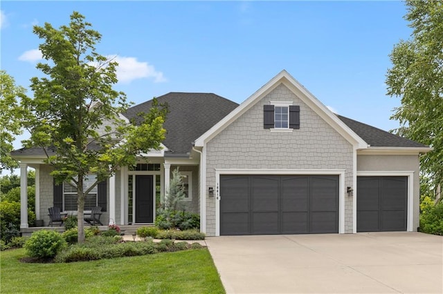 view of front of home with a front yard, roof with shingles, covered porch, concrete driveway, and a garage