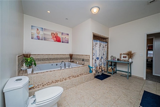 bathroom featuring tiled tub, tile patterned flooring, and toilet