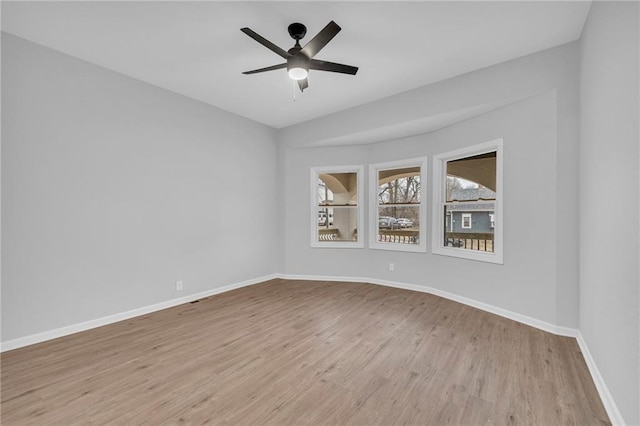 empty room with light wood finished floors, a ceiling fan, and baseboards